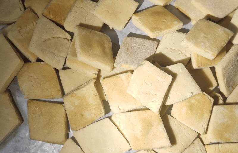 Cheese pet biscuits with a golden-brown baked finish, arranged on a baking tray.