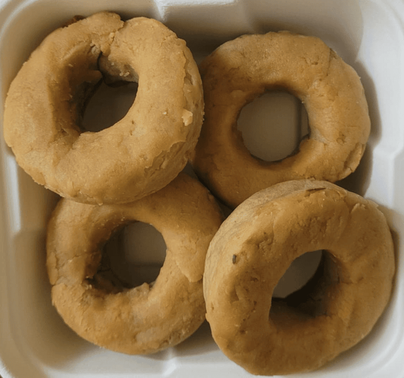 Peanut butter pet donuts with a golden-brown baked finish, arranged in a white dish.