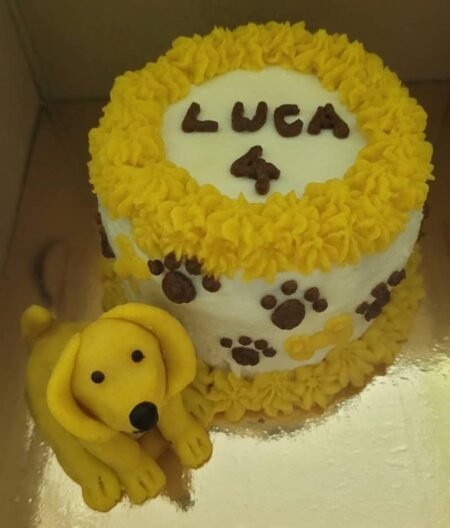 Pumpkin pet cake with yellow and white frosting, paw-print decorations, and a yellow dog topper, personalised with “LUCA”.