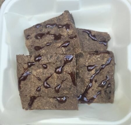 Pet-friendly chocolate-style brownies drizzled with a dark topping, arranged in a white container.