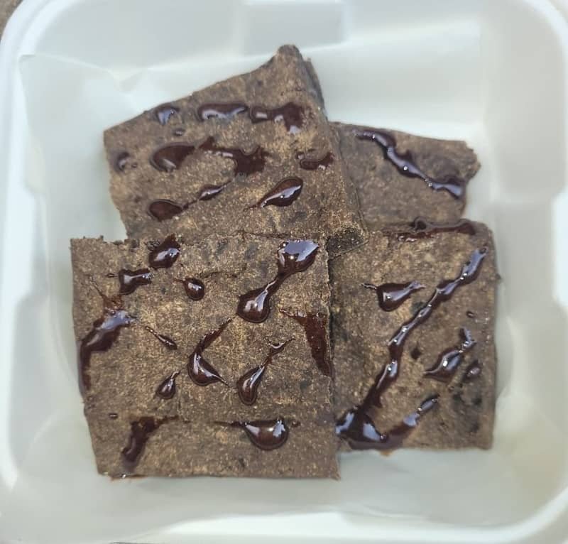 Pet-friendly chocolate-style brownies drizzled with a dark topping, arranged in a white container.