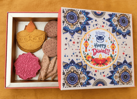 Open Diwali treats hamper from Pawradise Pet Bakery displaying four varieties of handcrafted festive pet biscuits beside the Happy Diwali gift box.