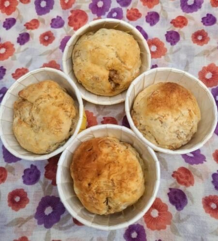 Freshly baked pet muffins with a golden-brown finish, arranged in four paper cups.