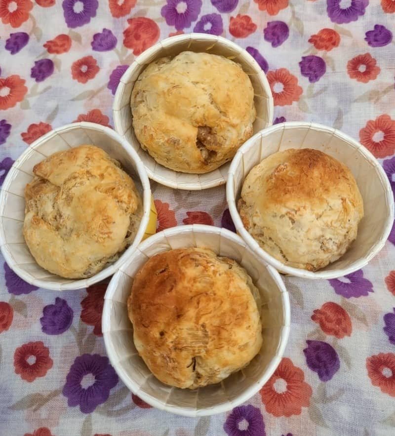 Freshly baked pet muffins with a golden-brown finish, arranged in four paper cups.