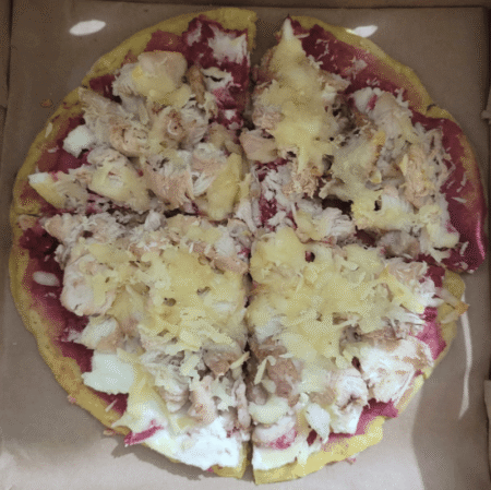 Chicken pet pizza topped with shredded chicken, mozzarella cheese and colourful vegetable toppings.