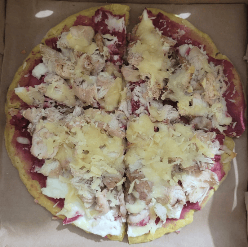 Chicken pet pizza topped with shredded chicken, mozzarella cheese and colourful vegetable toppings.