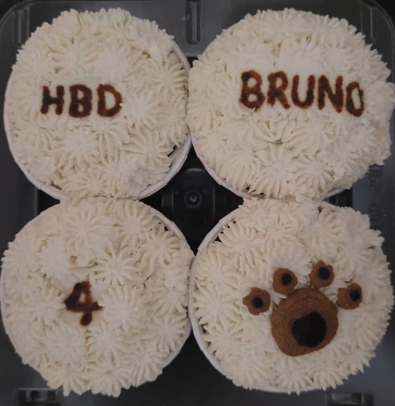 Pet cupcakes with white piped frosting, personalised with pet names and ages, including a paw-print design.