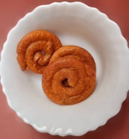 Pet jalebi treats served on a white scalloped plate.