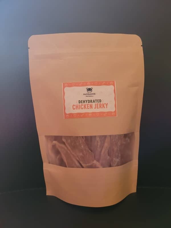 Front view of Pawradise Pet Bakery dehydrated chicken jerky with apple sauce in a brown stand-up pouch featuring branded packaging and a clear window.