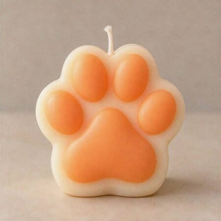 White and orange two-tone paw-shaped soy wax candle with a cotton wick.