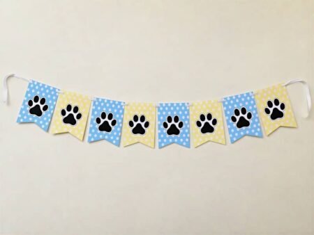 Pet birthday celebration banner featuring eight alternating pastel blue and yellow polka-dot pennants with black paw prints, strung together on a white ribbon.